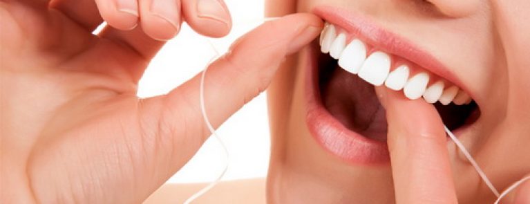 Pessoa fazendo usando fio dental | Quando devo fazer limpeza nos dentes?