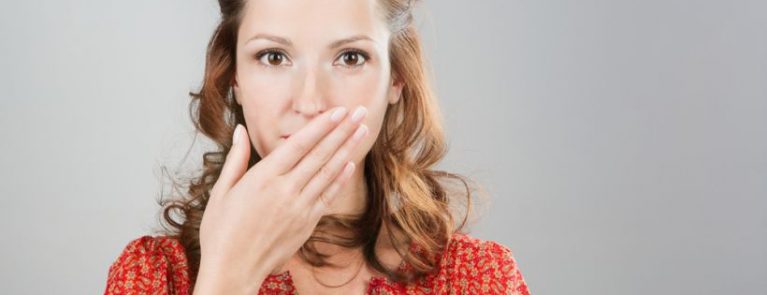 Mulher com a mão na boca | O que fazer quando perder um dente?