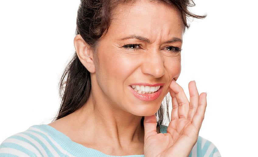 Mulher com dor de dente | O que é doença periodontal?